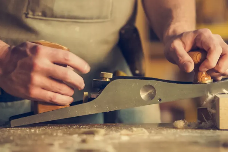 Artesano trabajando la madera con un cepillo de carpintero
